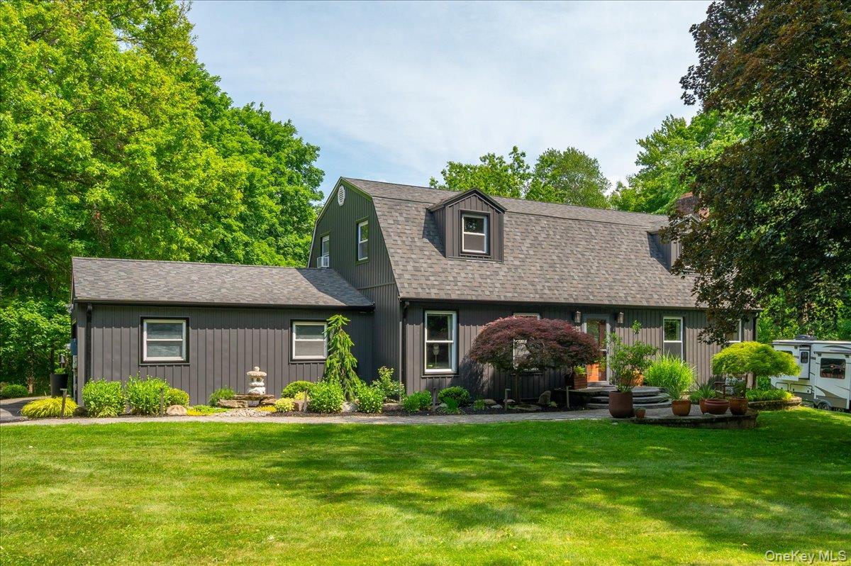 13 Jacks Pond Road Newburgh, NY 12550 - Photo 2 of 44 Board and batten siding home featuring a dormer window, mature landscaping, and a manicured lawn.
