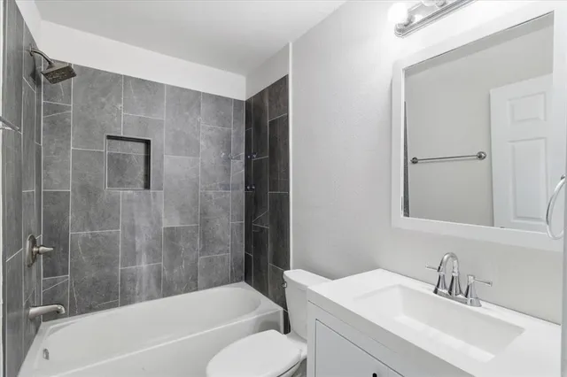 a bathroom with a bathtub shower sink vanity and toilet