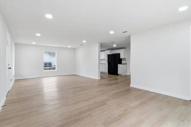 a view of an empty room with a window and a kitchen
