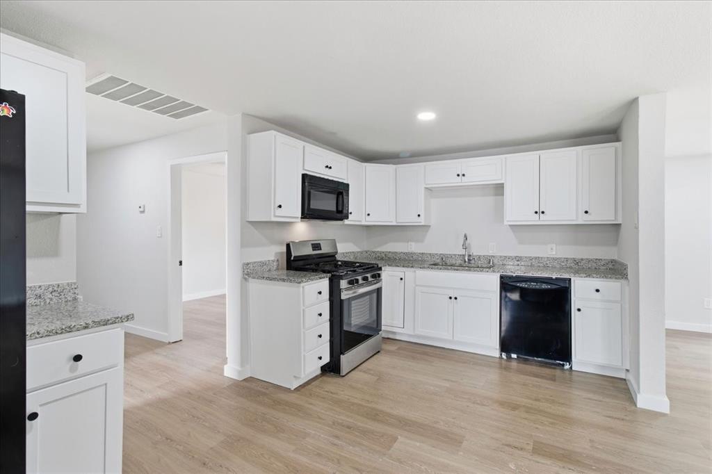 404 South Murray Street McKinney, TX 75069 - Photo 10 of 24 a kitchen with granite countertop white cabinets and stainless steel appliances