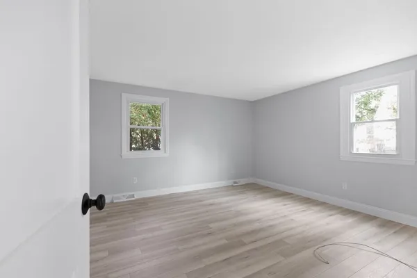 an empty room with wooden floor and windows