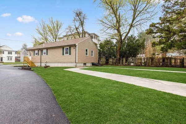 a view of a house with a big yard and large trees