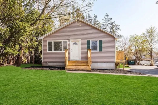 a front view of house with yard and trees in the background