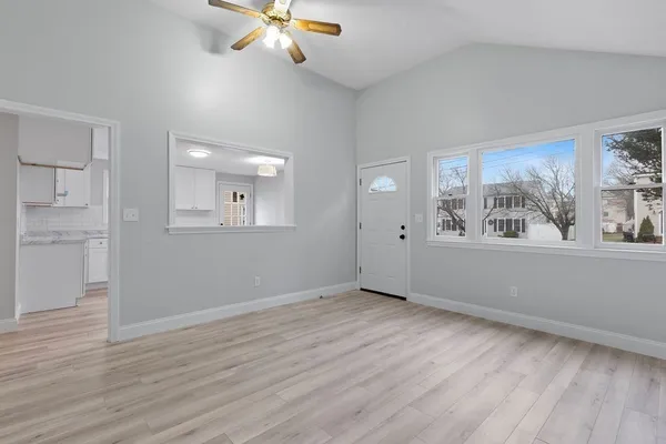 a view of an empty room with a window and wooden floor