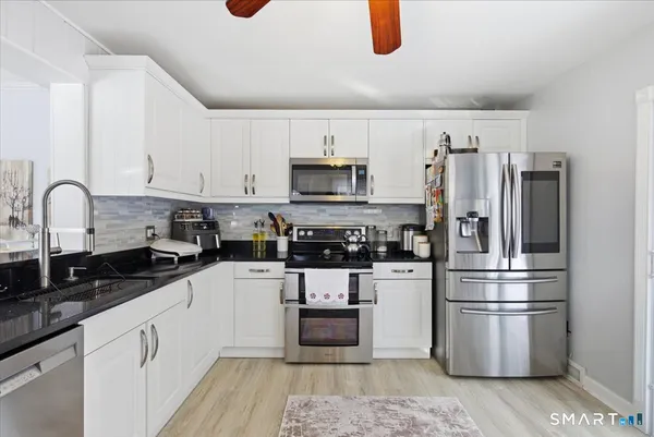 a kitchen with granite countertop a refrigerator and a stove top oven