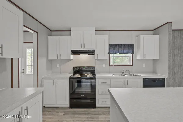 a kitchen with stainless steel appliances granite countertop a stove top oven a sink and white cabinets