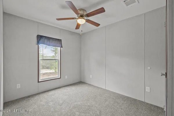 an empty room with windows and fan
