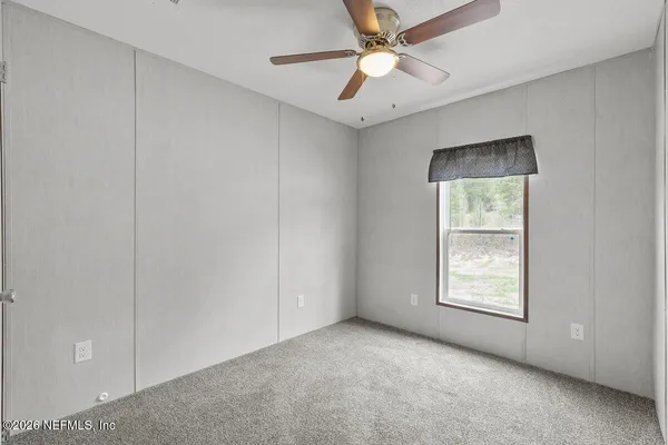 an empty room with windows and fan
