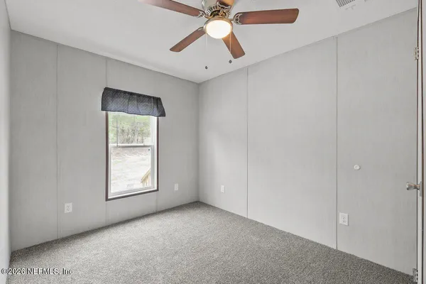 an empty room with closet and a chandelier fan