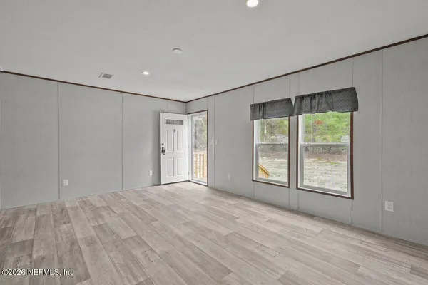 a view of an empty room with a window and wooden floor