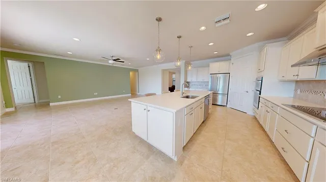 a large white kitchen with a large counter top appliances and cabinets