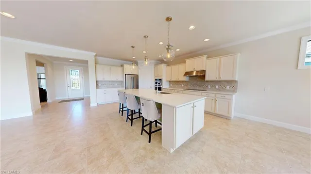 a kitchen with a sink a center island stainless steel appliances and cabinets