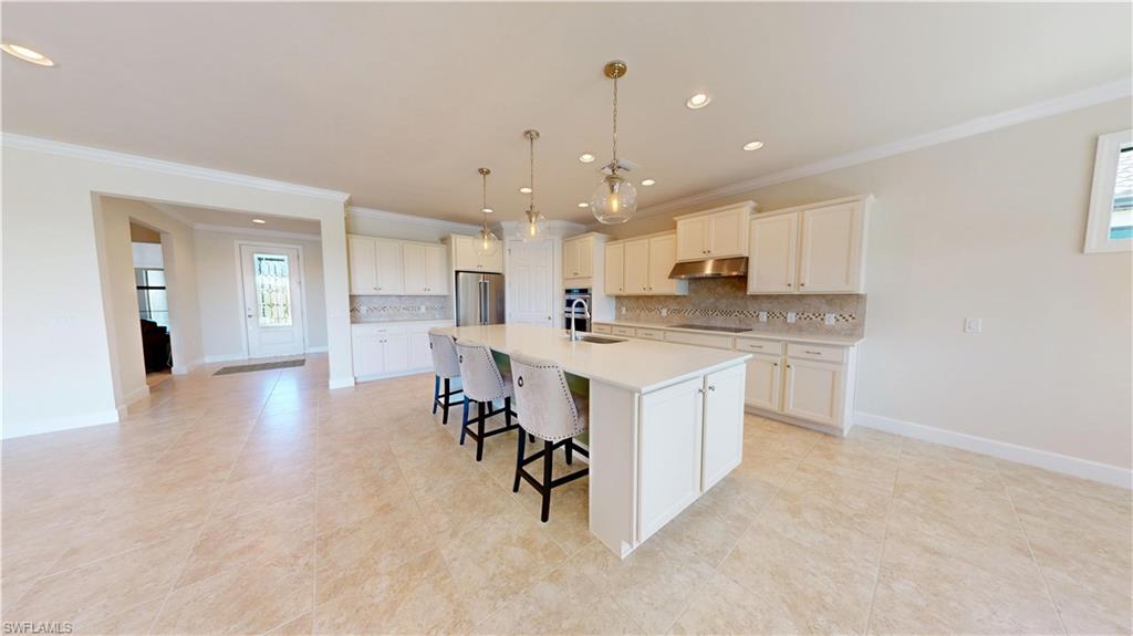 6354 Achievement Avenue Ave Maria, FL 34142 - Photo 12 of 50 a kitchen with a sink a center island stainless steel appliances and cabinets