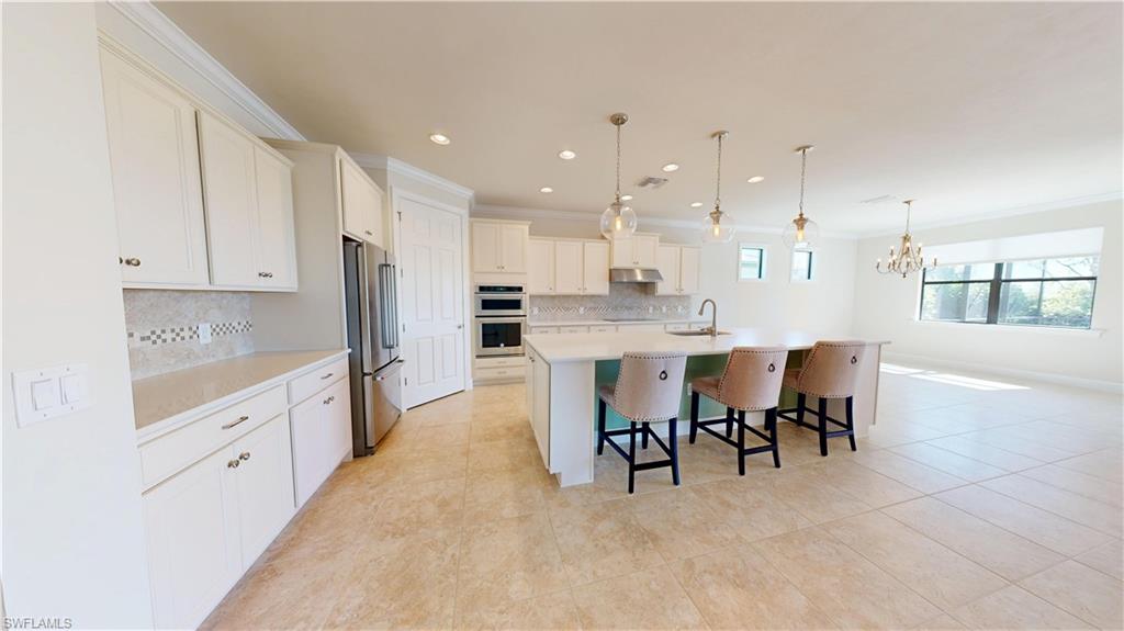 6354 Achievement Avenue Ave Maria, FL 34142 - Photo 4 of 50 a large kitchen with kitchen island granite countertop lots of white cabinets appliances and furniture