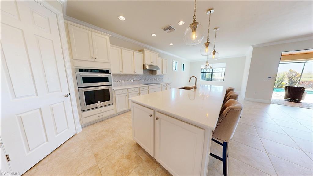 6354 Achievement Avenue Ave Maria, FL 34142 - Photo 5 of 50 a kitchen with stainless steel appliances a stove a sink a microwave a dining table and chairs