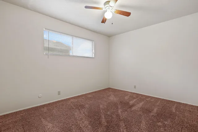an empty room with a ceiling fan and a window