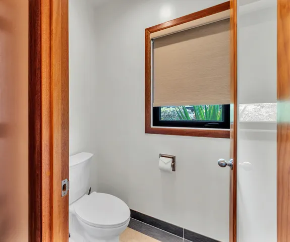 a white toilet sitting next to a small window