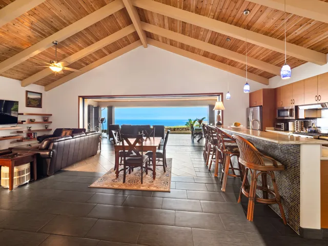 a dining hall with stainless steel appliances granite countertop a stove a sink a refrigerator with a dining table and chairs with the view of living room