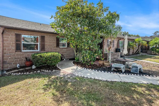 a view of a patio with table and chairs potted plants and large tree