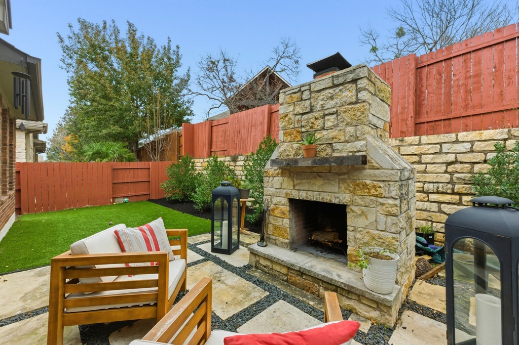 5425 Cherokee Draw Road Austin, TX 78738 - Photo 37 of 40 An inviting stone fireplace anchors this private outdoor living area, featuring paved patio and fenced yard.