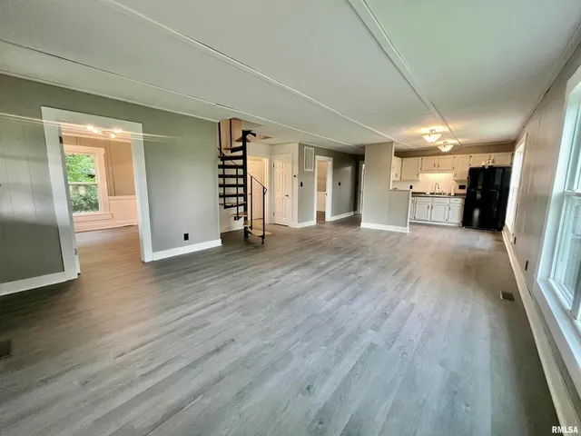 an empty room with wooden floor and entrance to ceiling window