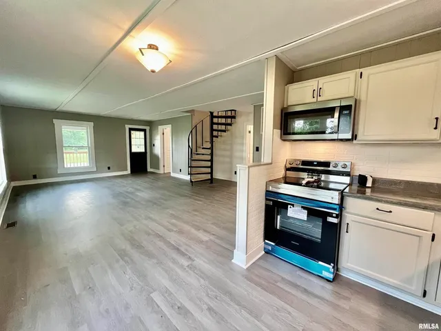 a kitchen with stainless steel appliances white cabinets and wooden floor
