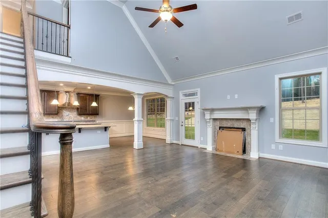 a view of a livingroom with a fireplace a ceiling fan and wooden floor