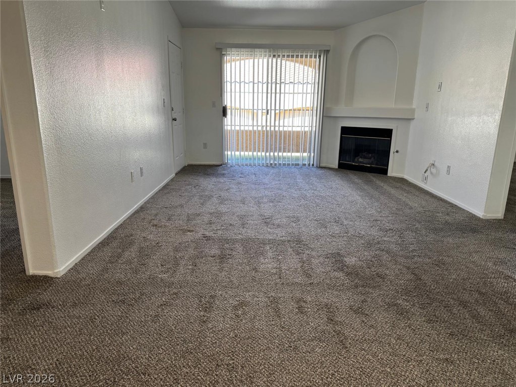 7885 West Flamingo Road, Unit 2171 Las Vegas, NV 89147 - Photo 8 of 22 A cozy living space features soft carpeting and a fireplace, inviting relaxation.