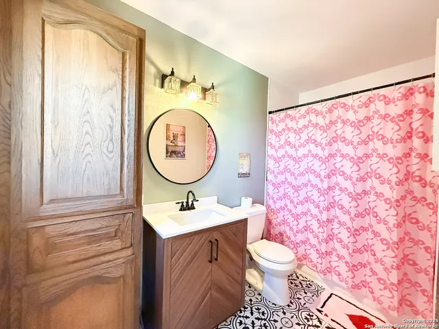 a bathroom with a sink toilet mirror vanity and shower