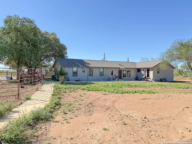 a front view of a house with a dirt yard and a large tree