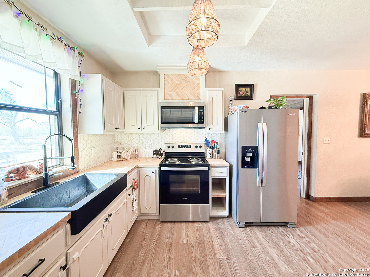 200 Pr 6631 Devine, TX 78016 - Photo 7 of 41 a kitchen with stainless steel appliances a stove a sink dishwasher a refrigerator and a microwave oven with wooden floor