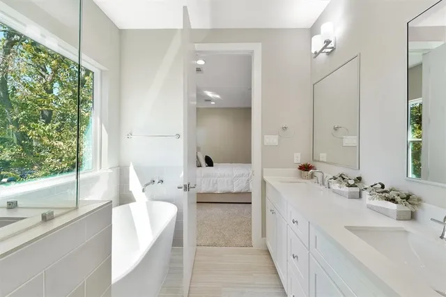 a spacious bathroom with a double vanity sink large mirror and a bathtub