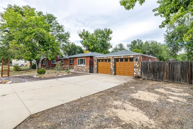 front view of house with a yard and a large trees