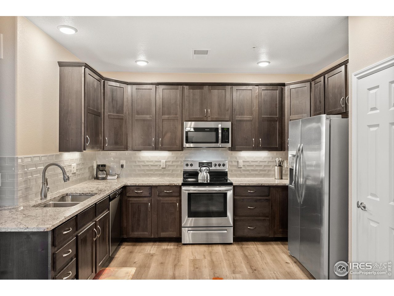 4672 West 20th Road, Unit 723 Greeley, CO 80634 - Photo 9 of 27 a kitchen with stainless steel appliances granite countertop a stove a sink dishwasher a refrigerator and a microwave