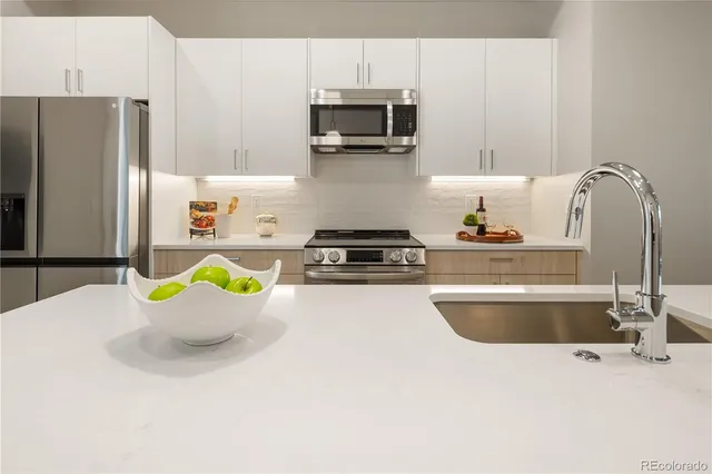 a kitchen with stainless steel appliances a stove a sink a microwave a refrigerator and cabinets