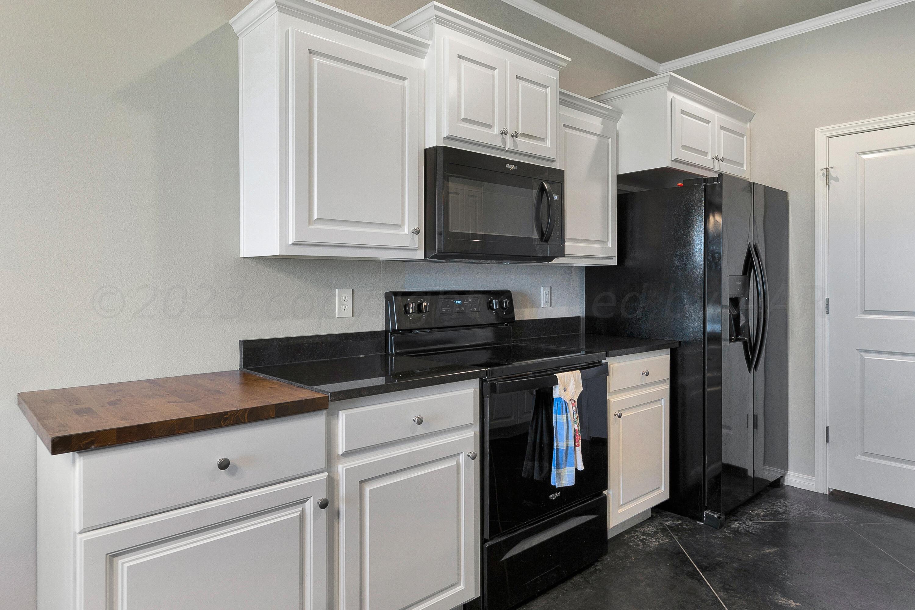9927 Perry Avenue Amarillo, TX 79119 - Photo 9 of 24 a kitchen with granite countertop a refrigerator stove and microwave