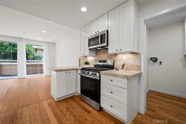 a kitchen with stainless steel appliances granite countertop a stove a sink and a microwave