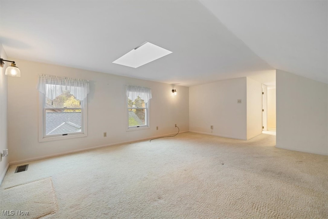4488 Rainbow Road Cleveland, OH 44121 - Photo 30 of 39 Additional living space featuring light colored carpet and lofted ceiling with skylight