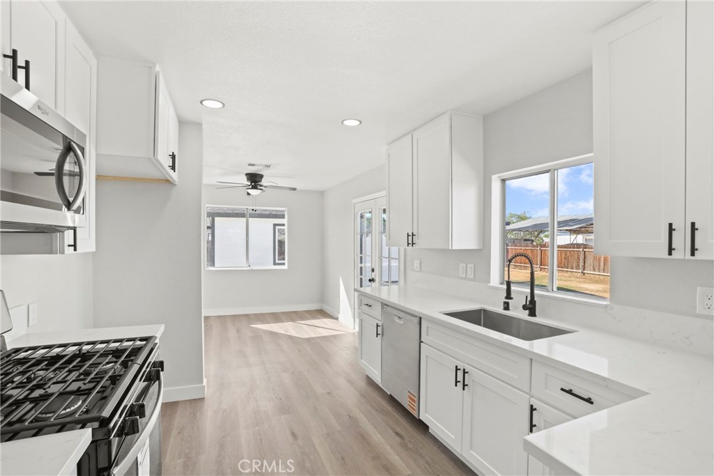 1116 7th Street Calimesa, CA 92320 - Photo 13 of 52 a large white kitchen with stainless steel appliances a large window a sink and a stove