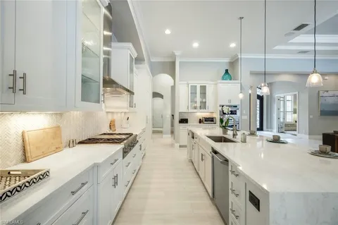 a large white kitchen with stainless steel appliances lots of counter space and a sink