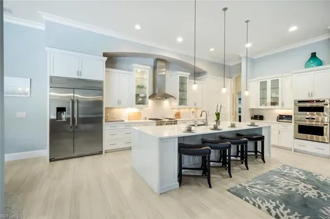 a large kitchen with cabinets chairs and wooden floor