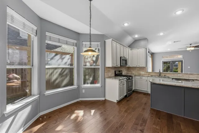 a kitchen with kitchen island granite countertop a stove a sink a center island and a wooden floor