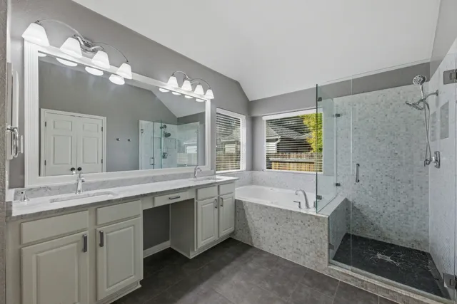 a bathroom with a tub a double vanity sink and a mirror