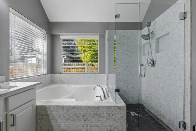 a bathroom with a bathtub a shower and a window