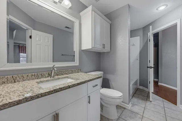 a bathroom with a granite countertop sink a toilet and a mirror