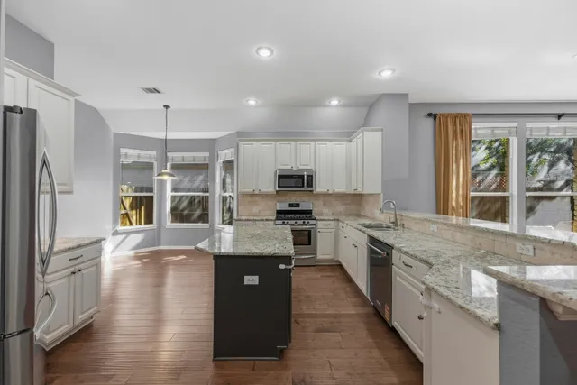 a large kitchen with stainless steel appliances granite countertop a lot of counter space and wooden floor