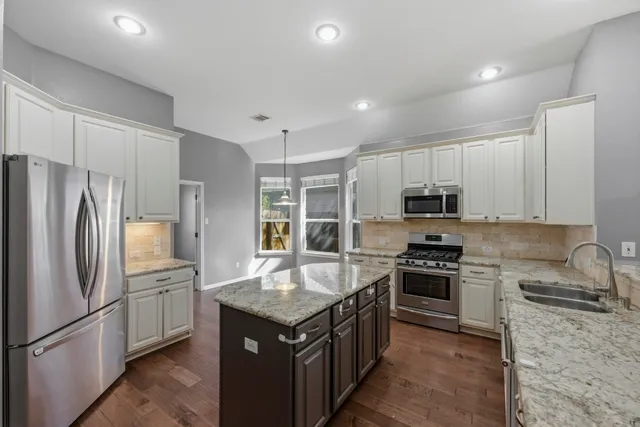 a kitchen with stainless steel appliances granite countertop a refrigerator stove and oven