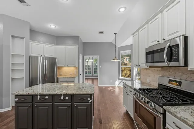 a kitchen with stainless steel appliances granite countertop a stove refrigerator sink and microwave