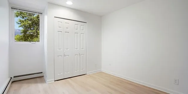 a view of an empty room with wooden floor and windows