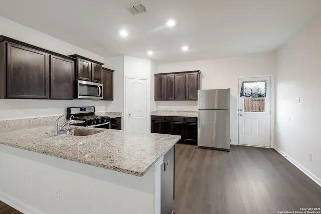 a kitchen with granite countertop a refrigerator stove and microwave